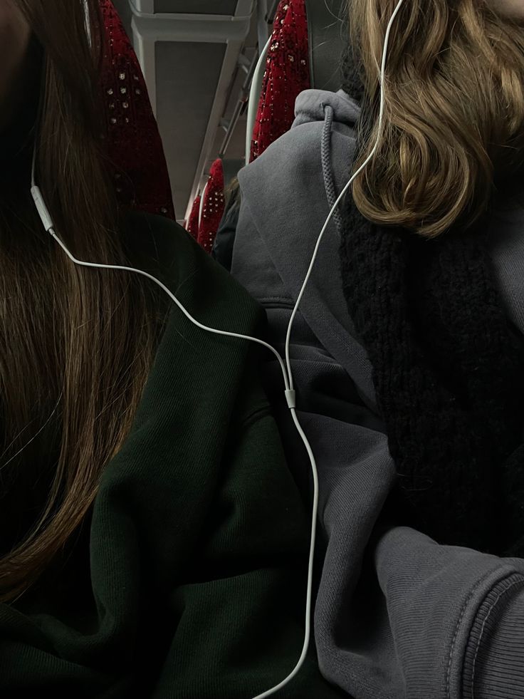 two women sitting on a bus with headphones in their ears