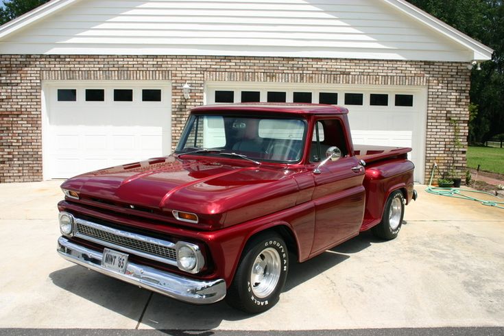 an old red pickup truck parked in front of a house