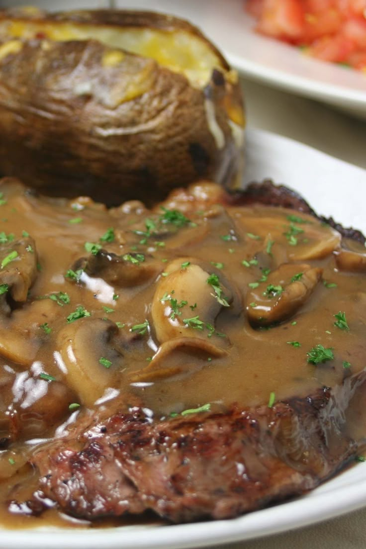 steak with mushrooms and gravy on a white plate