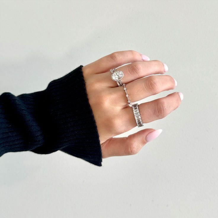 a woman's hand with three different rings on her fingers and one is wearing a black sweater