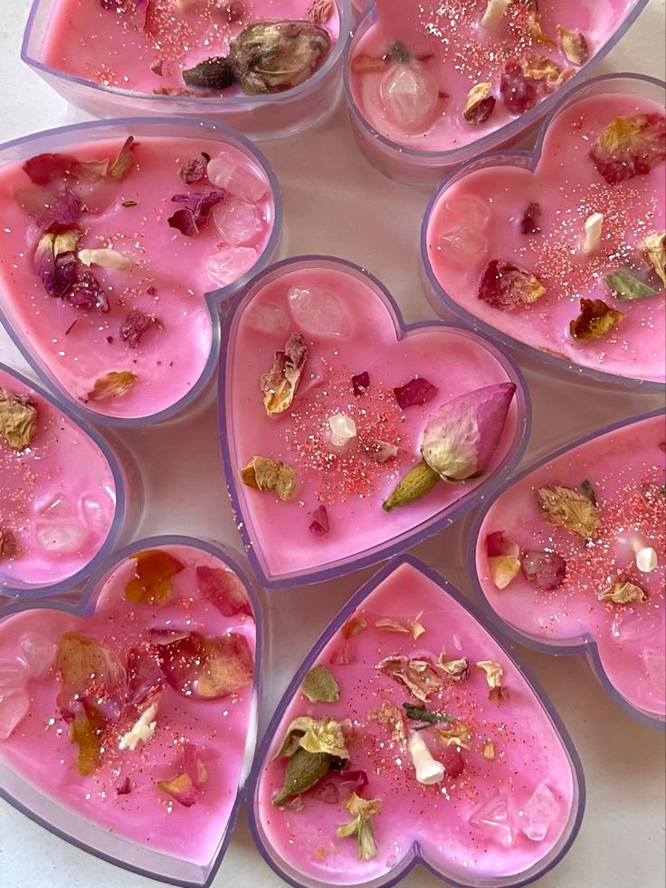 heart shaped bowls filled with different types of flowers and petals on top of a table