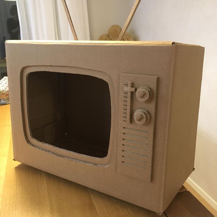 an old tv made out of cardboard sitting on the floor in front of a wall