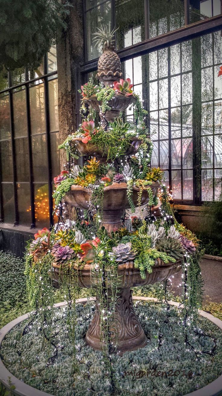 a very pretty fountain with some flowers in the middle of it's centerpiece