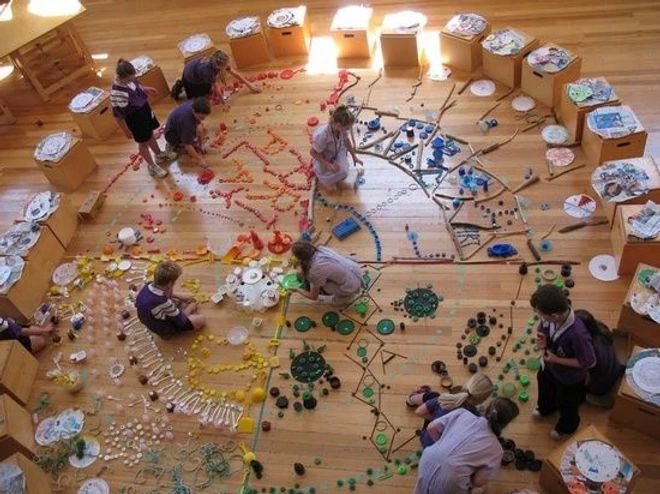 an overhead view of several children playing with beads and plates on the floor in a room