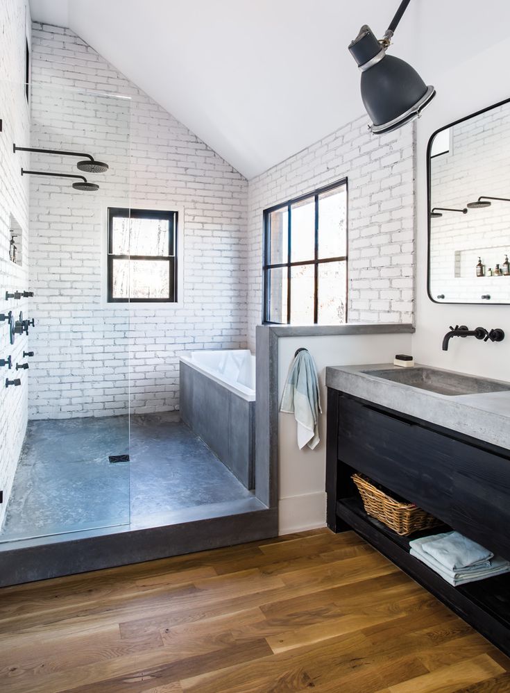 a bathroom with white brick walls and wood flooring, along with a walk in shower