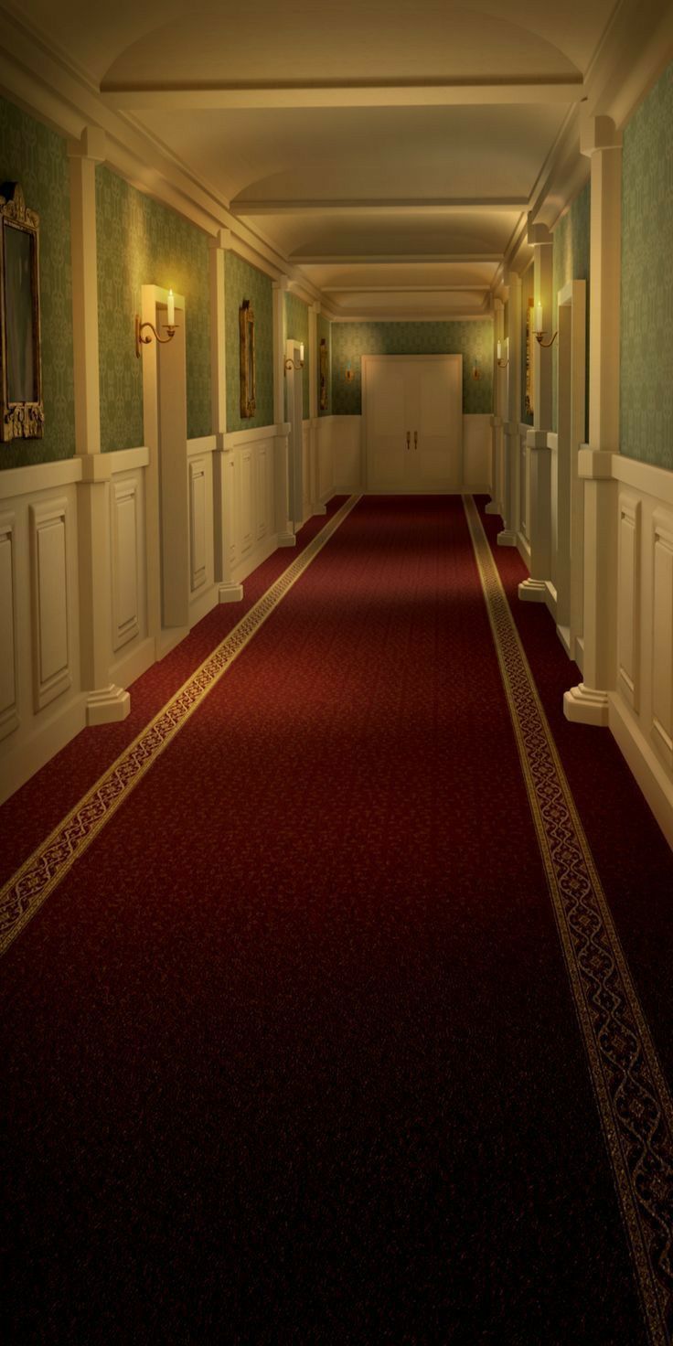 a long hallway with red carpet and white walls on either side is lit by two wall sconces