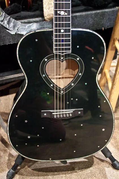 a black guitar sitting on top of a wooden chair