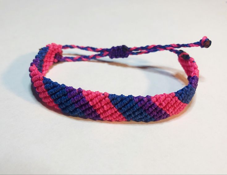 a close up of a bracelet on a white surface with blue, pink and purple beads