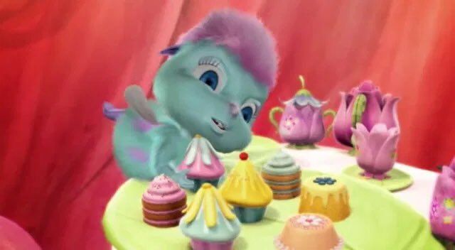 an animated blue dragon sitting at a table with cupcakes and cakes on it