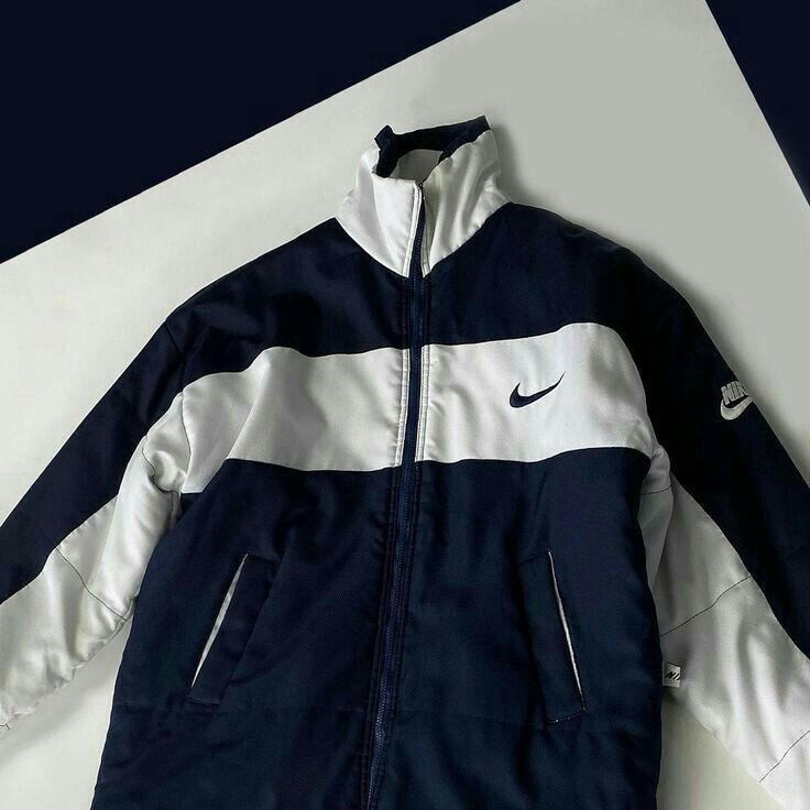 a blue and white nike jacket sitting on top of a table next to a pair of scissors