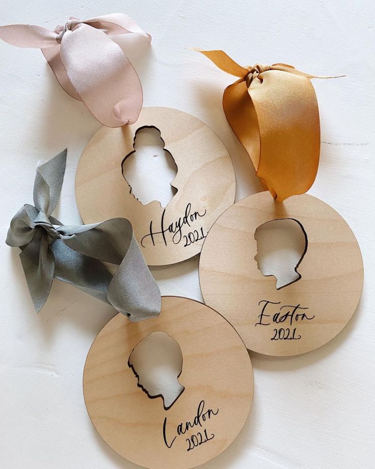 four personalized wooden ornaments with ribbons on them