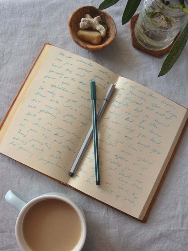 an open notebook with writing on it next to a cup of coffee