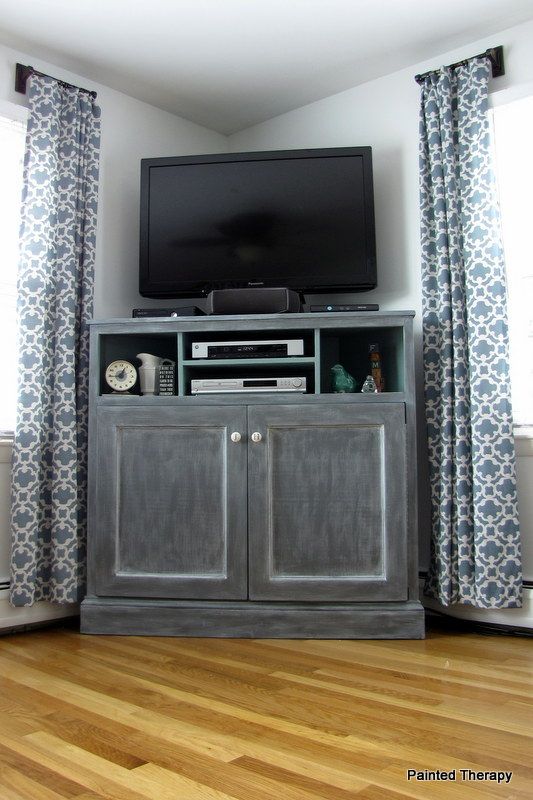 a flat screen tv sitting on top of a wooden cabinet in front of a window