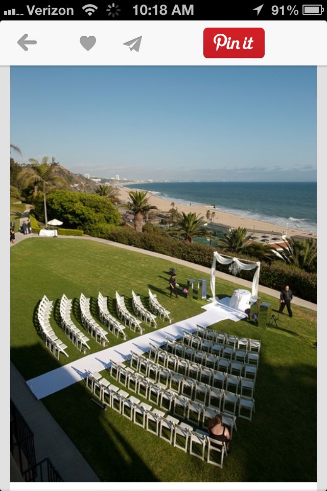 an aerial view of a lawn with rows of white chairs set up for a wedding ceremony