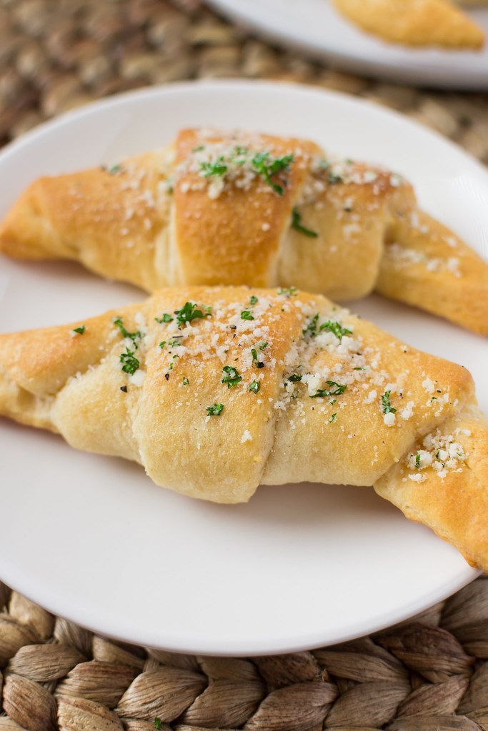 two pastries on a white plate with parmesan sprinkled toppings