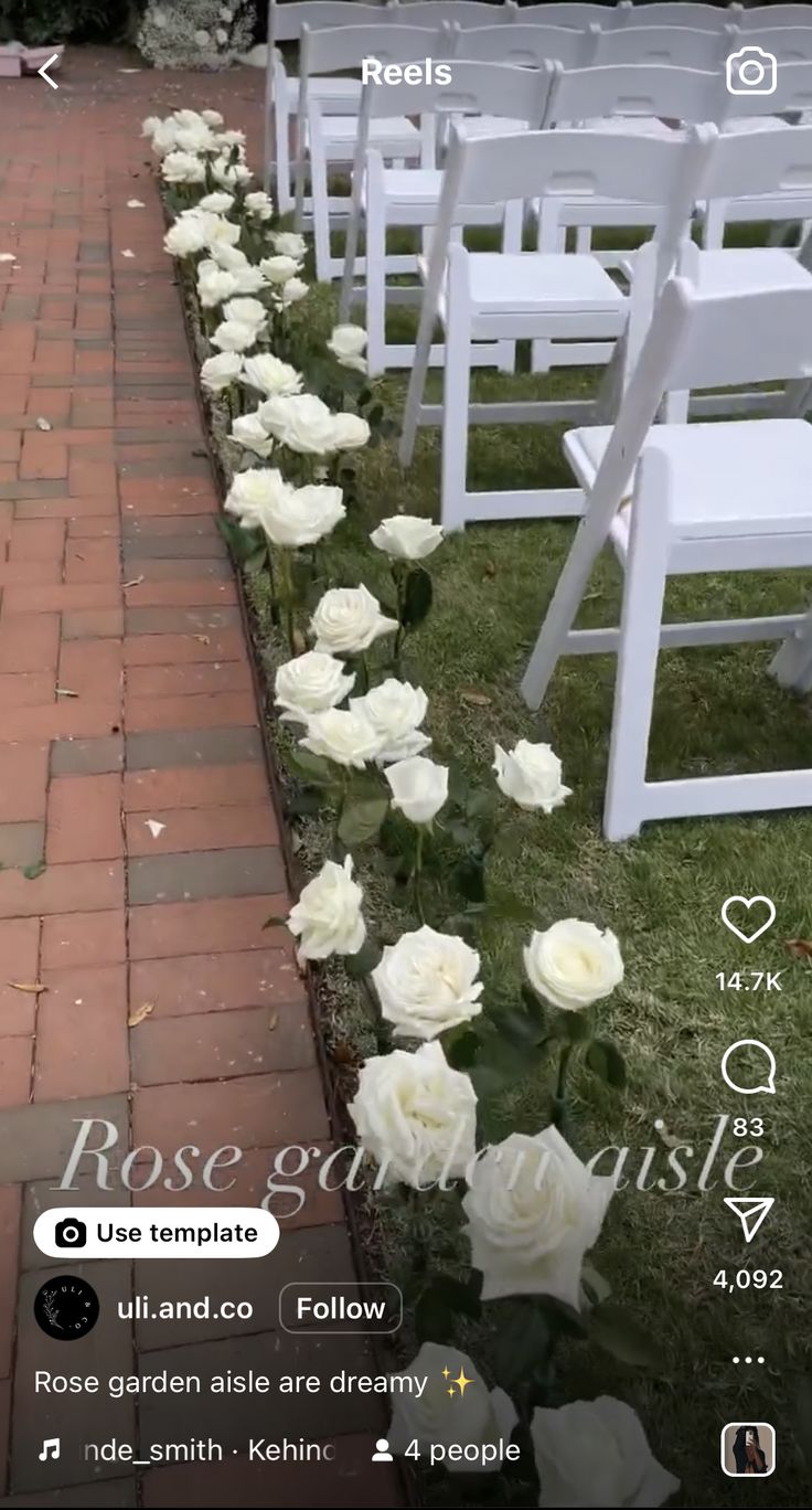 rows of white chairs lined up with flowers on the ground and in between them is a brick walkway