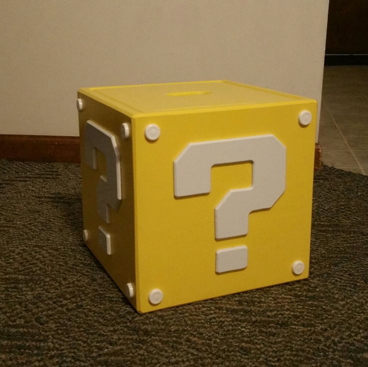 a yellow box with a question mark painted on it sitting on the floor next to a wall