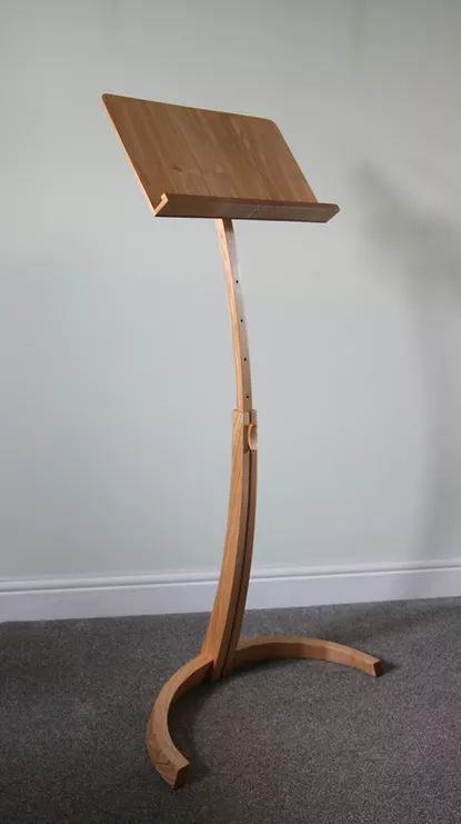 a wooden stand with a laptop on it's side in a room that has carpeted flooring and white walls