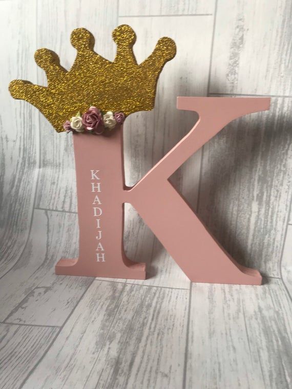 the letter k is decorated with flowers and a gold crown on it's head