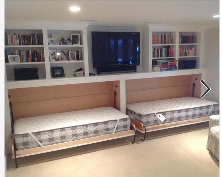 there are two beds in this room with built - in bookshelves on the wall