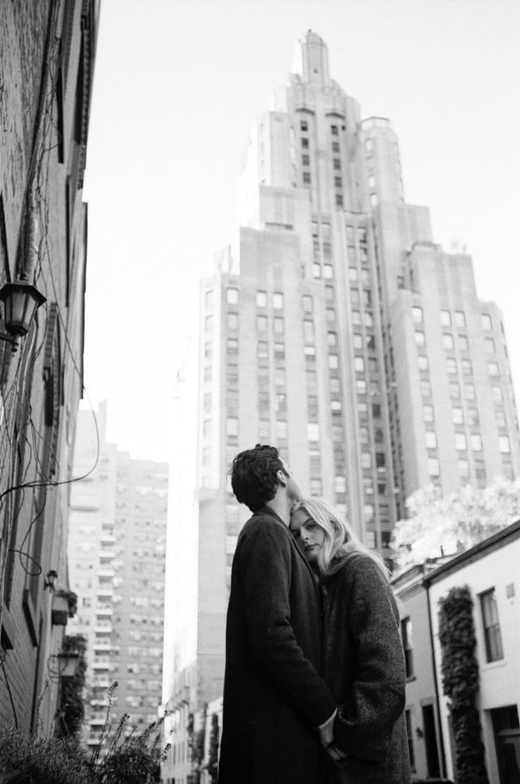 black and white photograph of two people standing in front of tall buildings