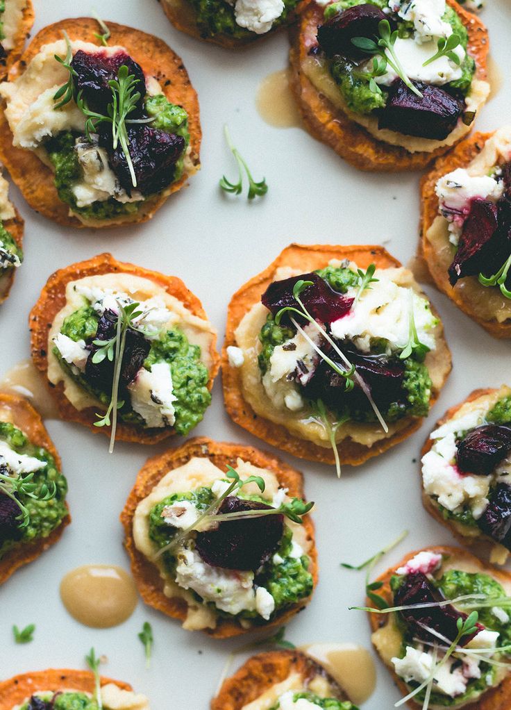 small appetizers are arranged on a white plate with green garnishes