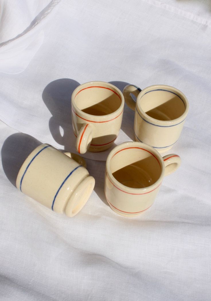 four coffee cups sitting on top of a white sheet