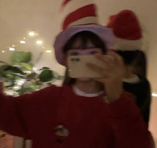 a woman taking a selfie in front of a christmas tree with the cat in the hat on