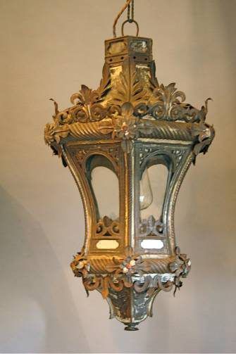 an ornate light hanging from the ceiling in a room with white walls and flooring