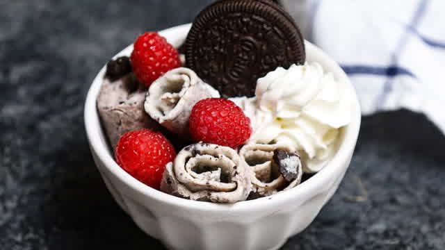 a bowl filled with ice cream, raspberries and oreo cookies on top