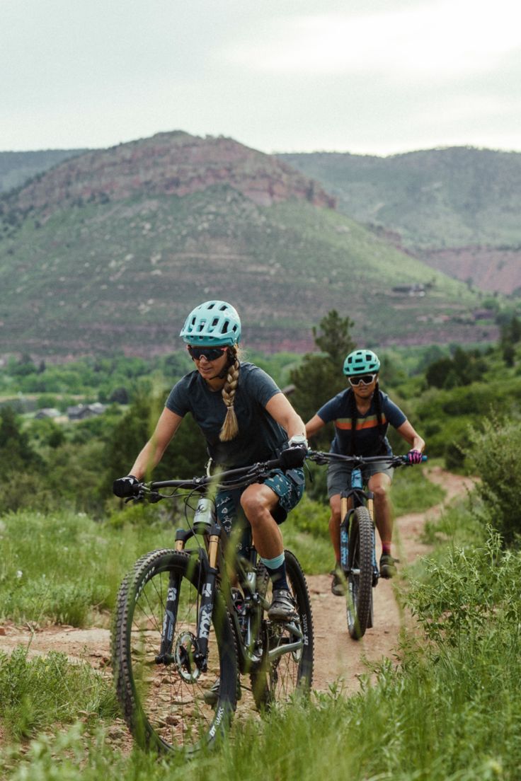 two people riding bikes on a dirt trail