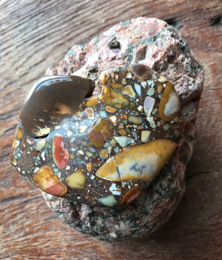 a rock covered in lots of different types of rocks and pebbles on top of a wooden table