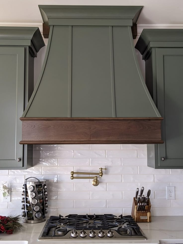 a stove top oven sitting inside of a kitchen next to green cupboards and white counter tops