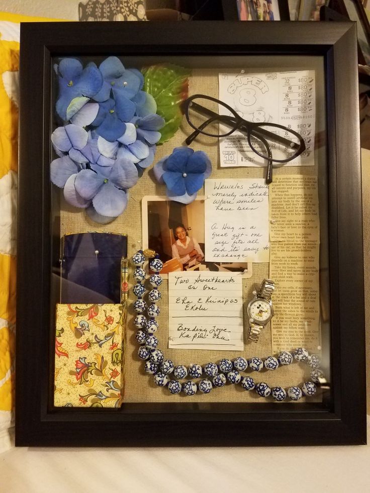 a framed photo with blue flowers and other items in it on top of a bed