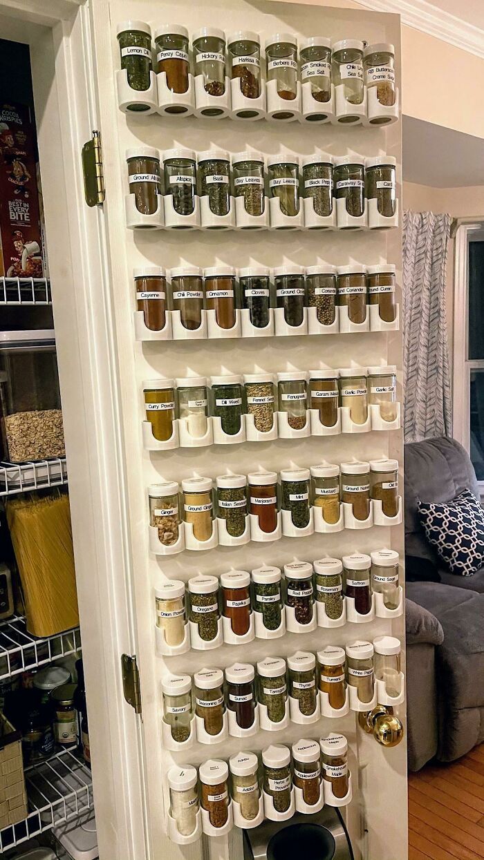 an organized spice rack in the corner of a living room with lots of jars on it