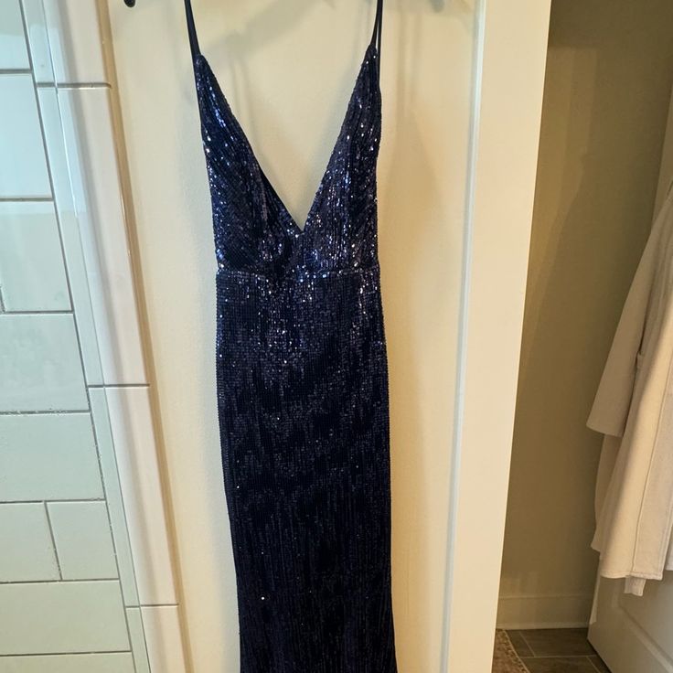 a blue dress hanging on a white wall next to a towel rack in a bathroom