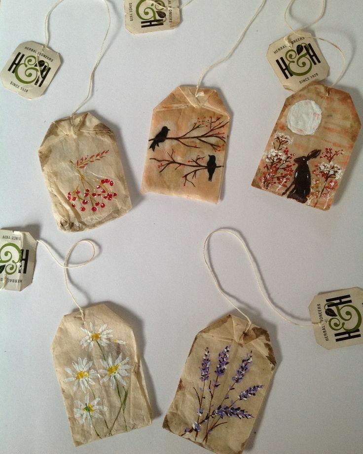 six tags with flowers and birds are hanging from strings on a white surface, surrounded by other tags