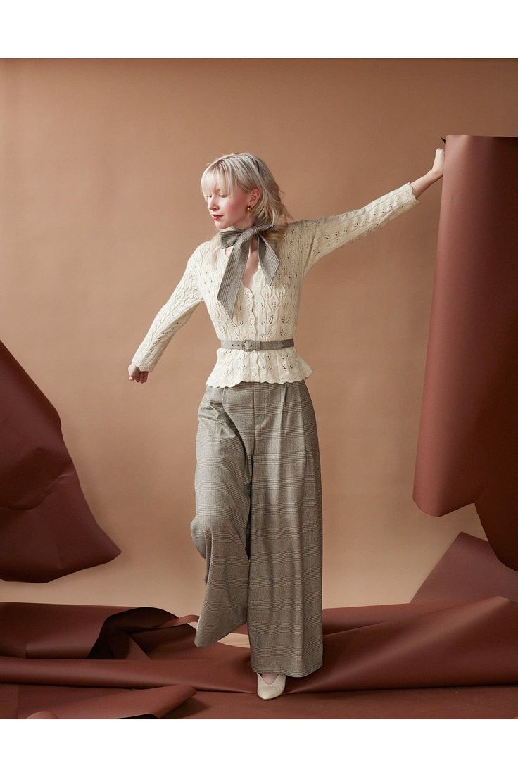 a woman standing in front of a brown background with her arms out and hands outstretched