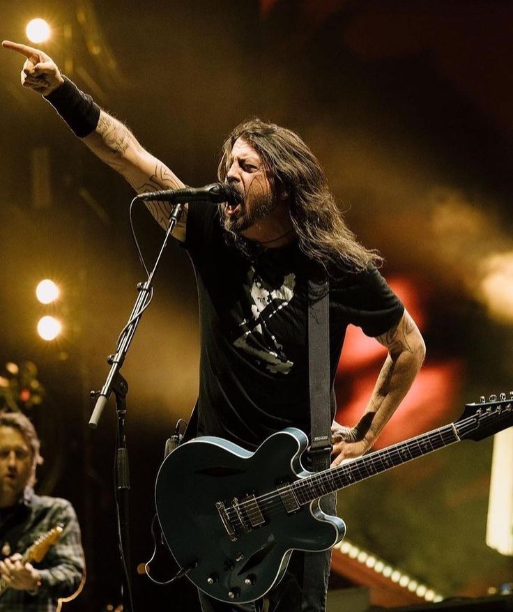 a man with long hair playing guitar on stage