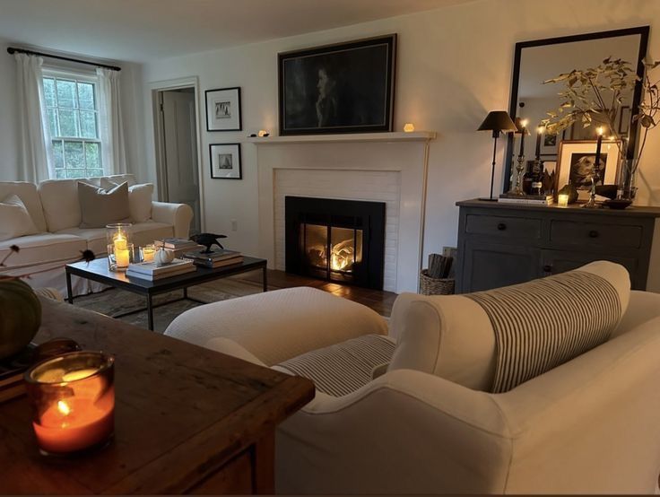 a living room filled with furniture and a fire place next to a window covered in candles