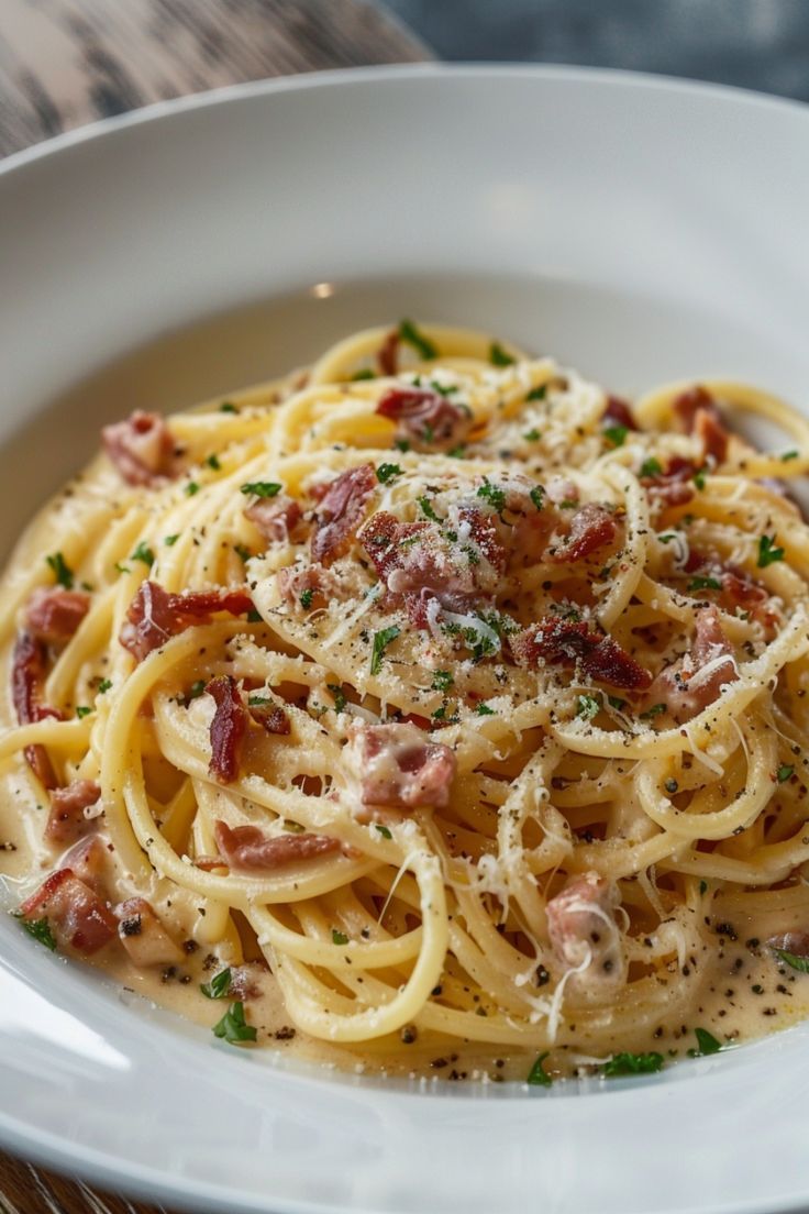 pasta with bacon and parmesan cheese in a white bowl on a wooden table