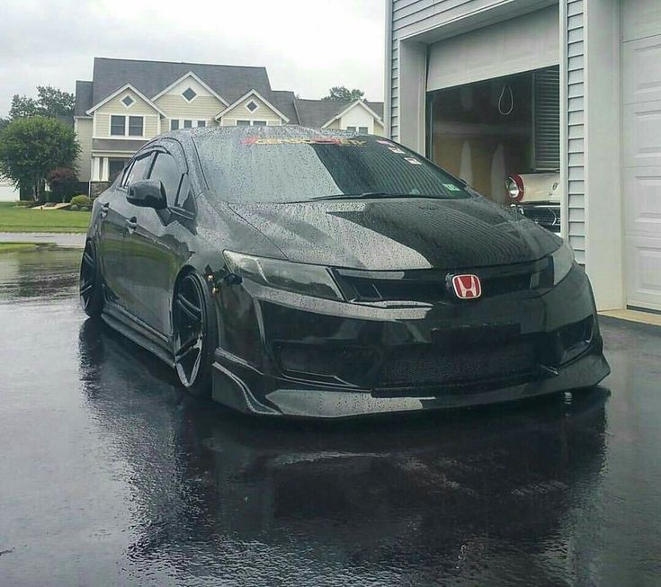 a car parked in front of a garage on a rainy day with the door open