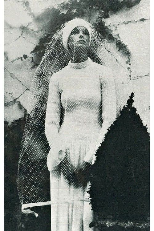 an old black and white photo of a woman with a veil on her head standing in front of a wall