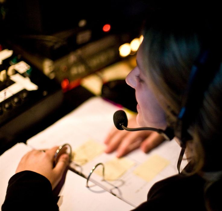 a woman sitting at a desk with a microphone in her hand and papers on the table next to her