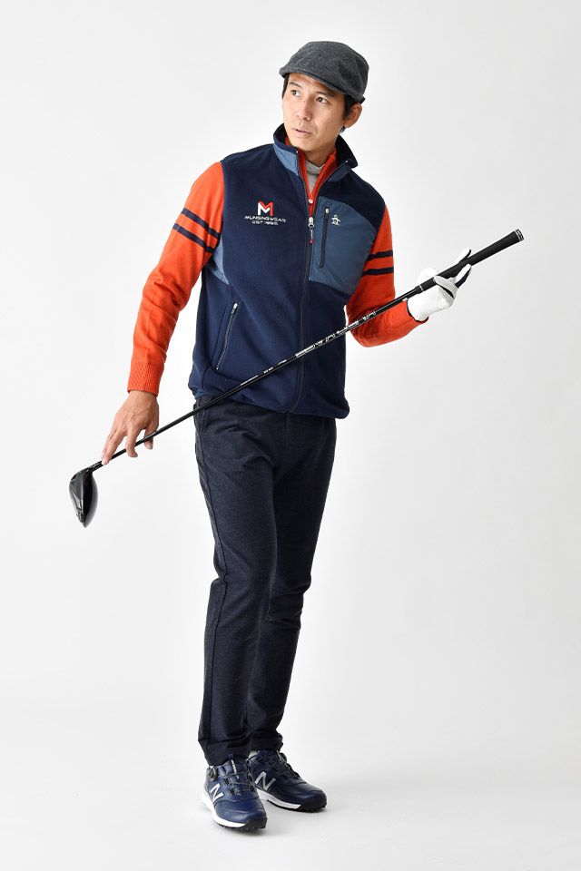 a man in an orange and blue jacket is holding two ski poles while standing on a white background