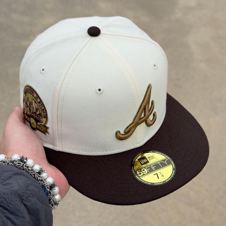 a person holding up a baseball cap with the letter a on it's side