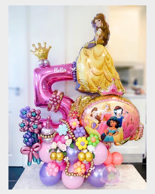 the birthday cake is decorated with balloons and princesses, including an air - filled number five