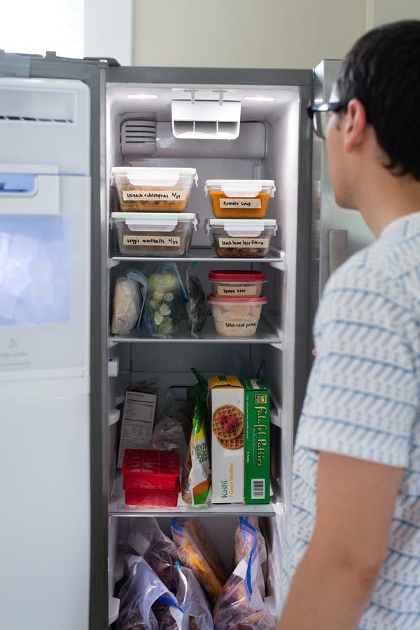 a man standing in front of an open refrigerator filled with food and drink items,