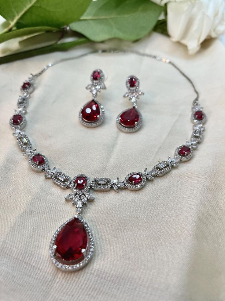 Unveil your inner elegance with our Red Ruby Cubic Zirconia Jewelry Set featuring a captivating necklace. This exquisite collection highlights the rich allure of vibrant red rubies, each piece masterfully crafted to perfection. Perfect for adding a touch of luxury and sophistication to any occasion, this set exudes timeless beauty and refined craftsmanship. Experience the enchanting charm of our Red Ruby Cubic Zirconia Jewelry Set and make a bold statement. Luxury Ruby Necklaces With Diamond Accents, Luxury Ruby Necklace With Diamond Accents, Red Crystal Necklaces For Celebrations, Wedding Fine Jewelry Necklace With Lab-created Ruby, Fine Jewelry Wedding Necklace With Lab-created Ruby, Fine Jewelry Lab-created Ruby Necklace For Wedding, Fine Jewelry Lab-created Ruby Necklaces For Wedding, Lab-created Ruby Necklaces For Wedding, Elegant Lab-created Ruby Jewelry For Valentine's Day