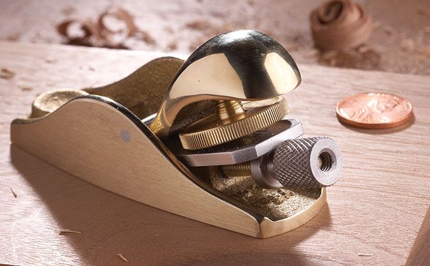 a metal object sitting on top of a wooden table next to a penny and knife